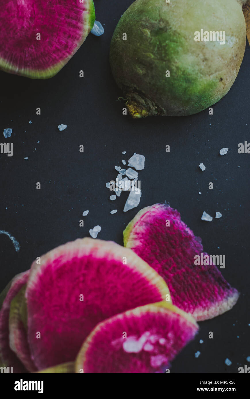 Watermelon Radishes Sliced, Sprinkled with Sea Salt on a black background Stock Photo