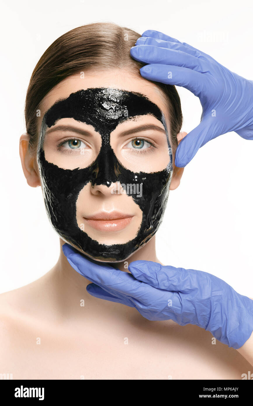 Young beautiful woman applying a mask for the face of the therapeutic black mud. Spa treatment Stock Photo