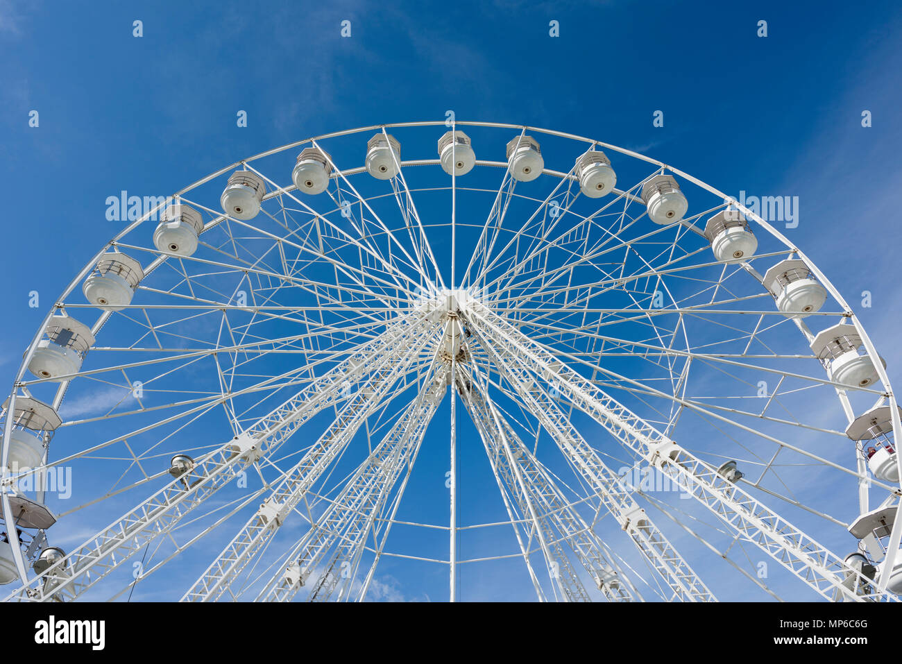A Ferris wheel, or big wheel, at a fairground against a blue sky. Stock Photo