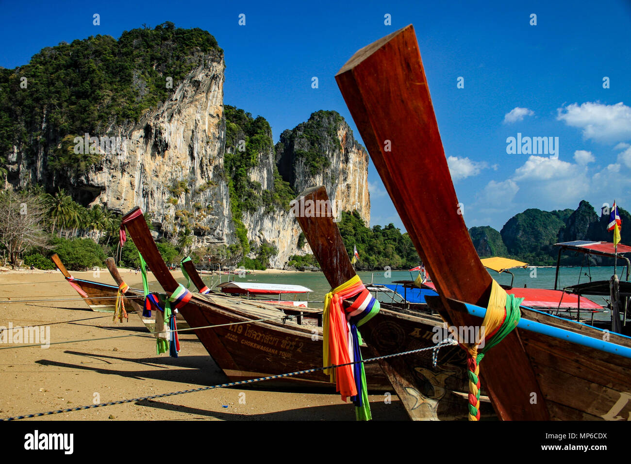 Long tail boats with karst cliffs and blue sky in background on West Railay, Tonsai, Beach, Thailand Stock Photo