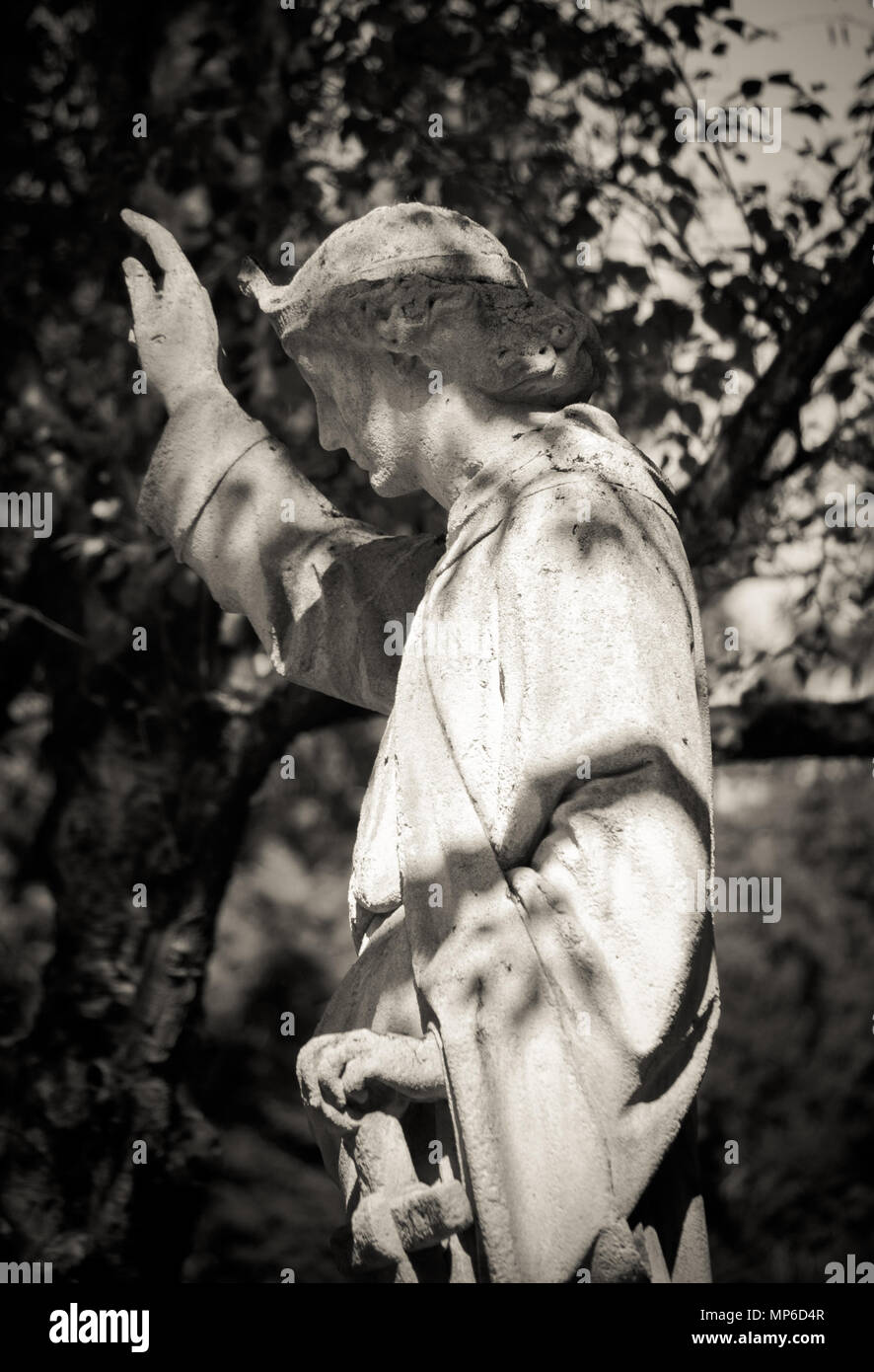 Angel stone figure on Melaten Cemetery in cologne on a summer day. Black and white. Light and shadow. Stock Photo