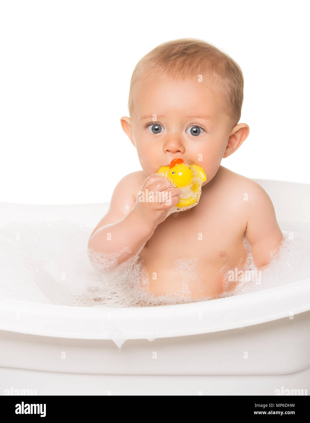 Adorable caucasian baby boy in a white bathtub with bubble bath. The kid is playing with a