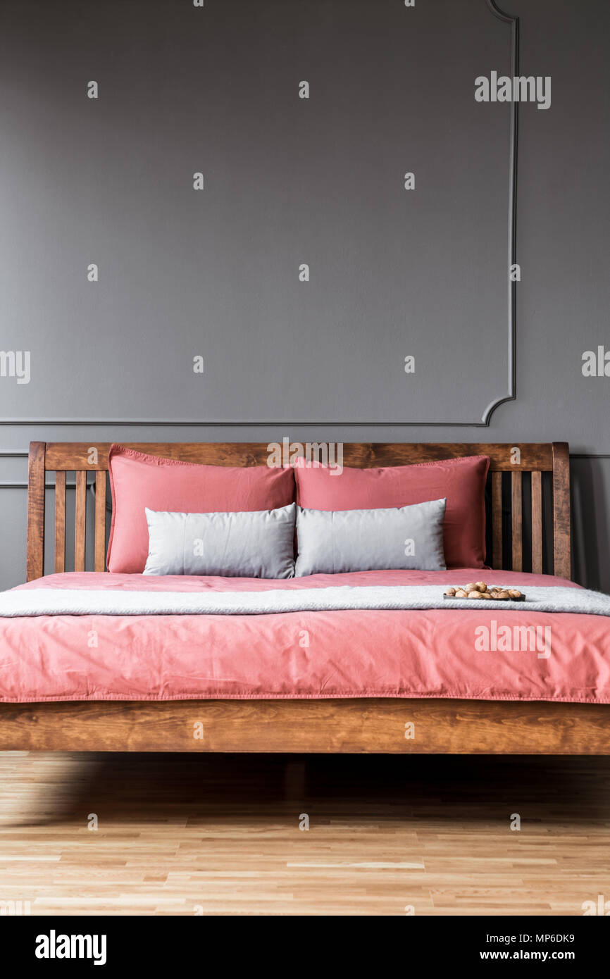 Close Up Of A Simple Bed With Wooden Bedhead And Pink Sheets In Dark Elegant Bedroom Interior With Molding On Dark Walls Real Photo Stock Photo Alamy