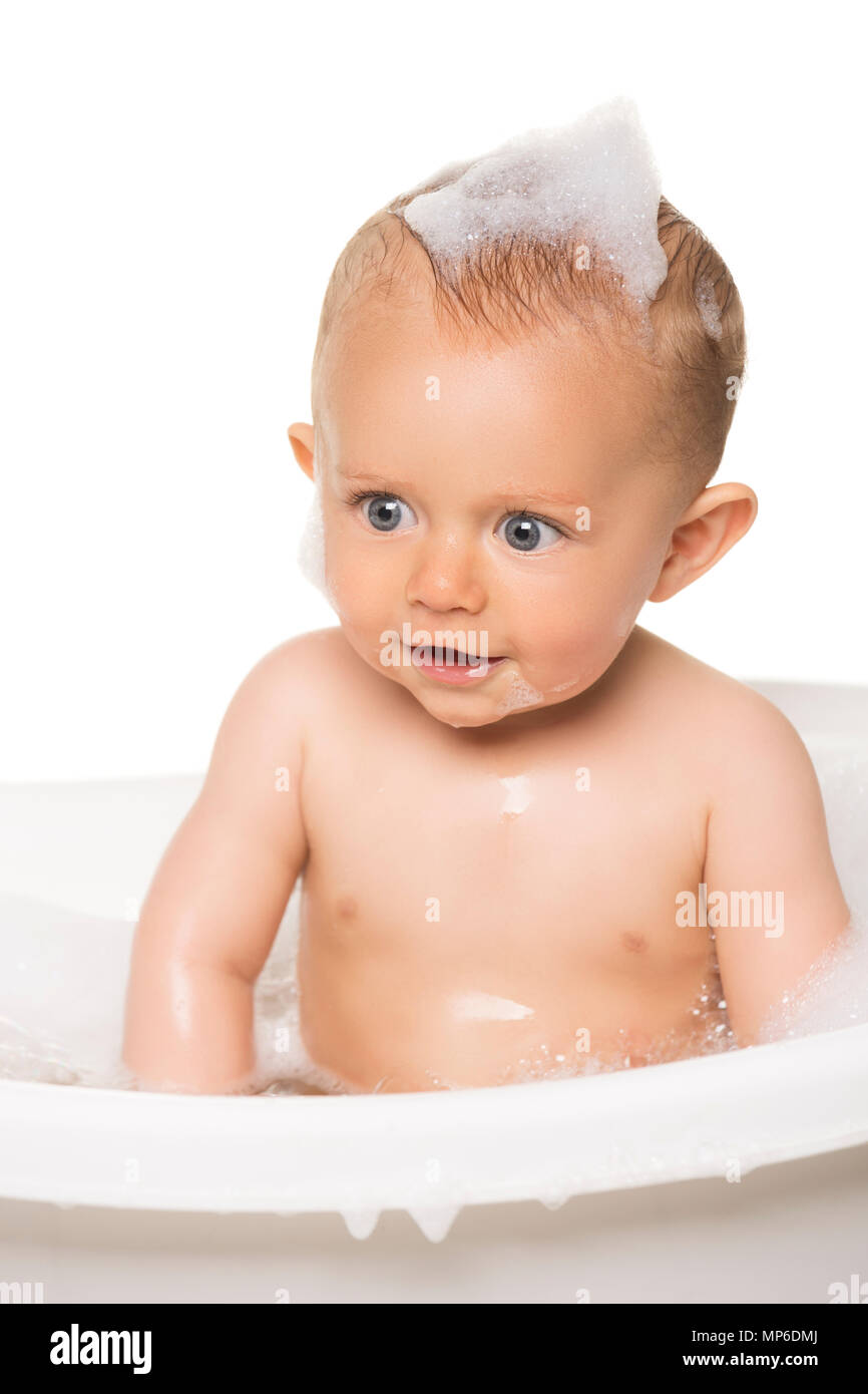 Adorable caucasian baby boy in a white bathtub with bubble bath Stock