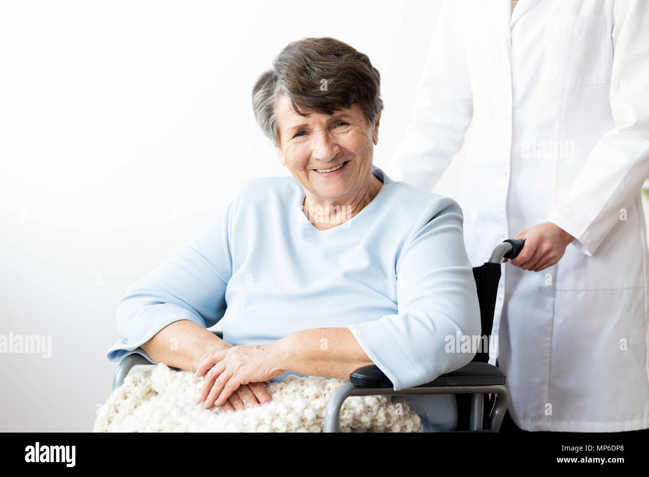 Smiling disabled senior woman in a wheelchair in the nursing house Stock Photo