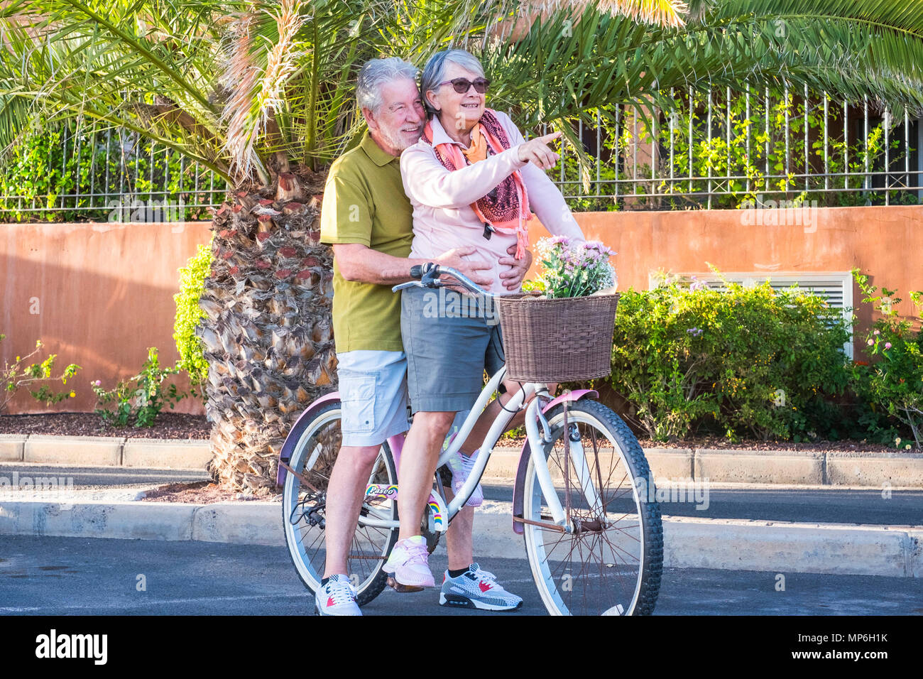 senior couple in love leisure outdoor together on a bike vintage style smiling and having fun under the sun of vacation. alternative way to be retired Stock Photo
