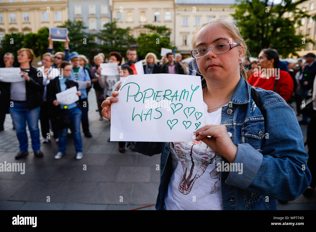 A disable teenager holds a banner saying ' we support you ' during a  protest to show solidarity for the ongoing protest inside the Parliament by  parents of  disabled in Krakow. Stock Photo