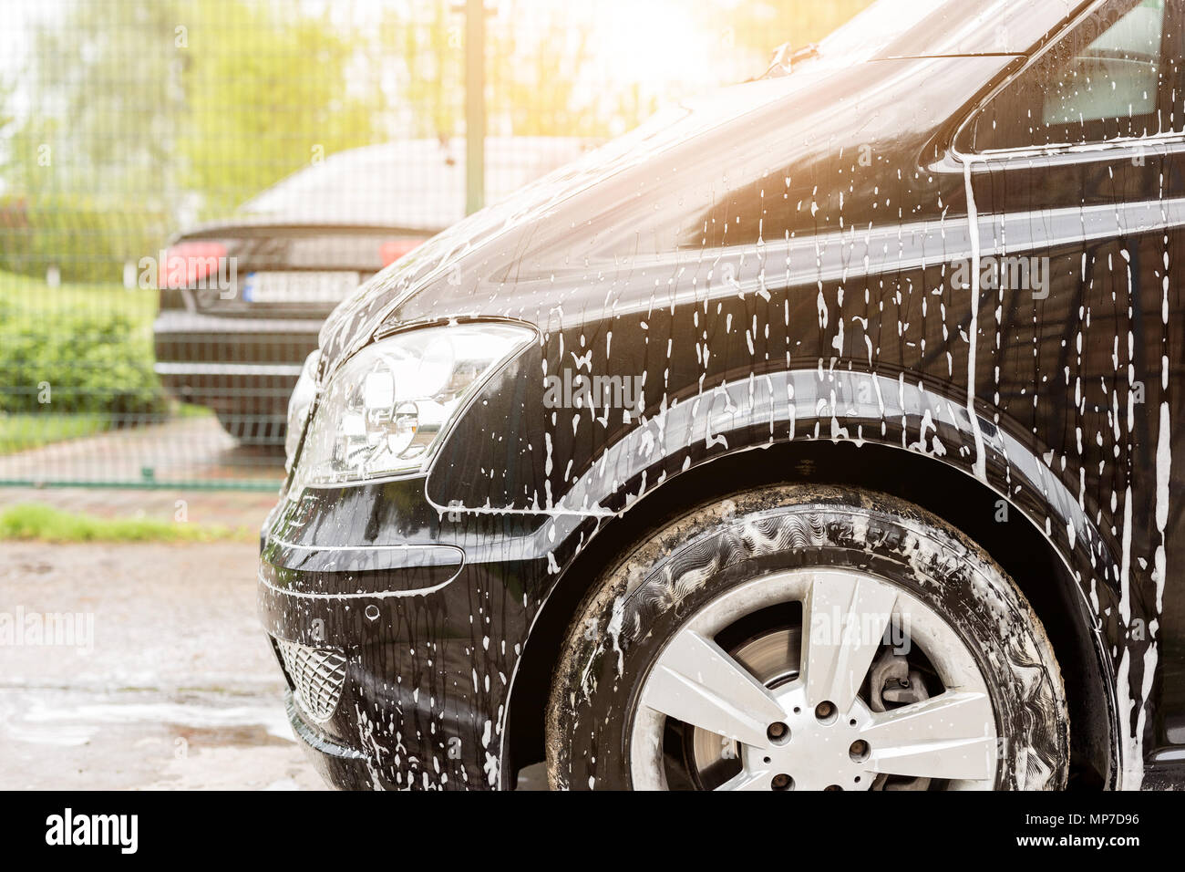 Manual car wash. Washing luxury vehicle with white foamy detergent
