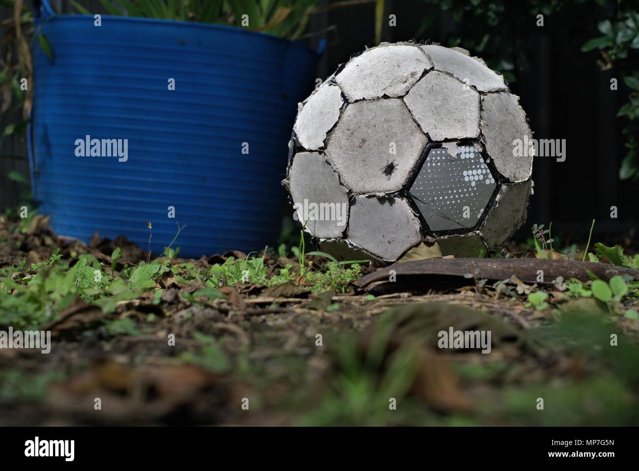 Torn up old soccer ball lay on grass. Worn out football. Concept of inactive person or useless object. Stock Photo