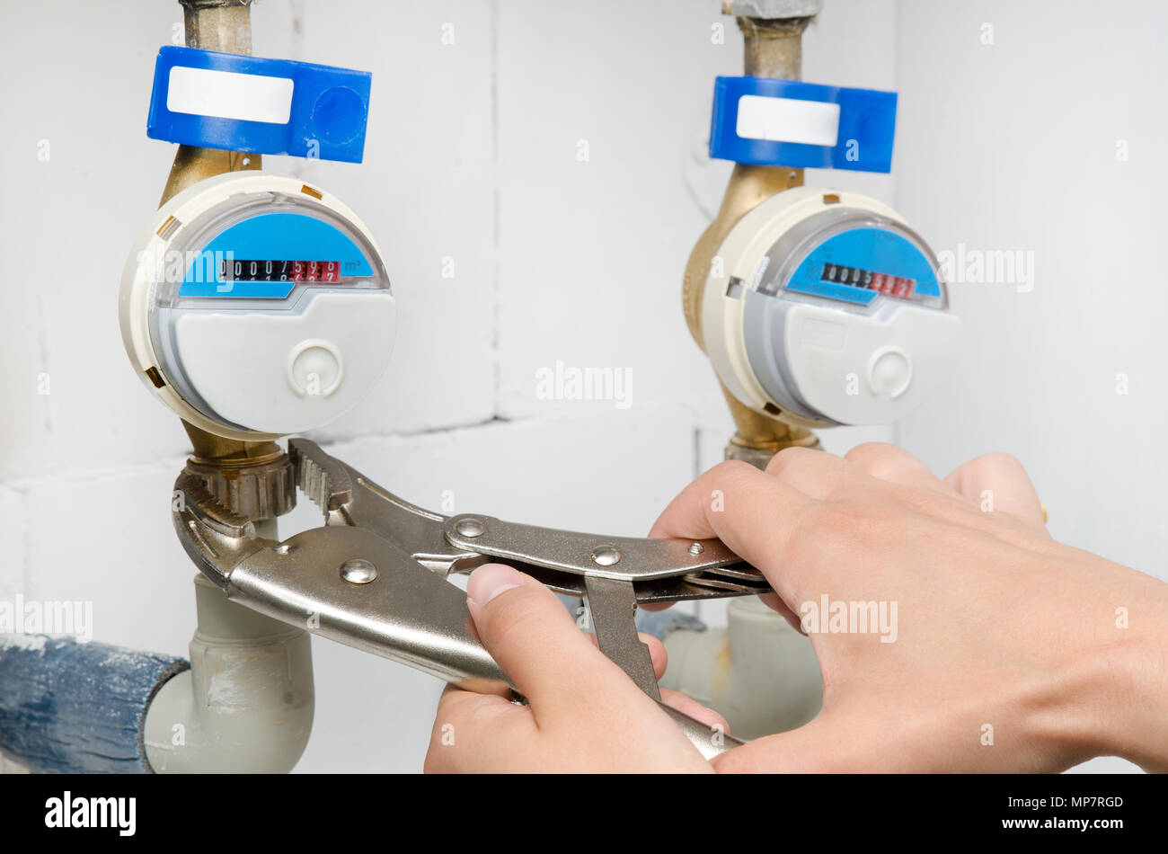 Technician installs a new water meter. Blue modern radio water counter. Man hand holding wrench. Stock Photo