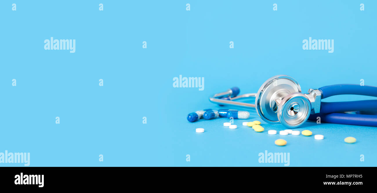 Stethoscope and pills on blue background copy space for web, internet banner Stock Photo