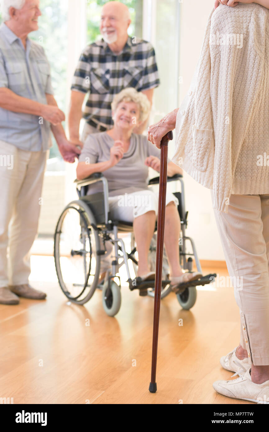 Senior person with a walking stick during meeting with friends in nursing house Stock Photo