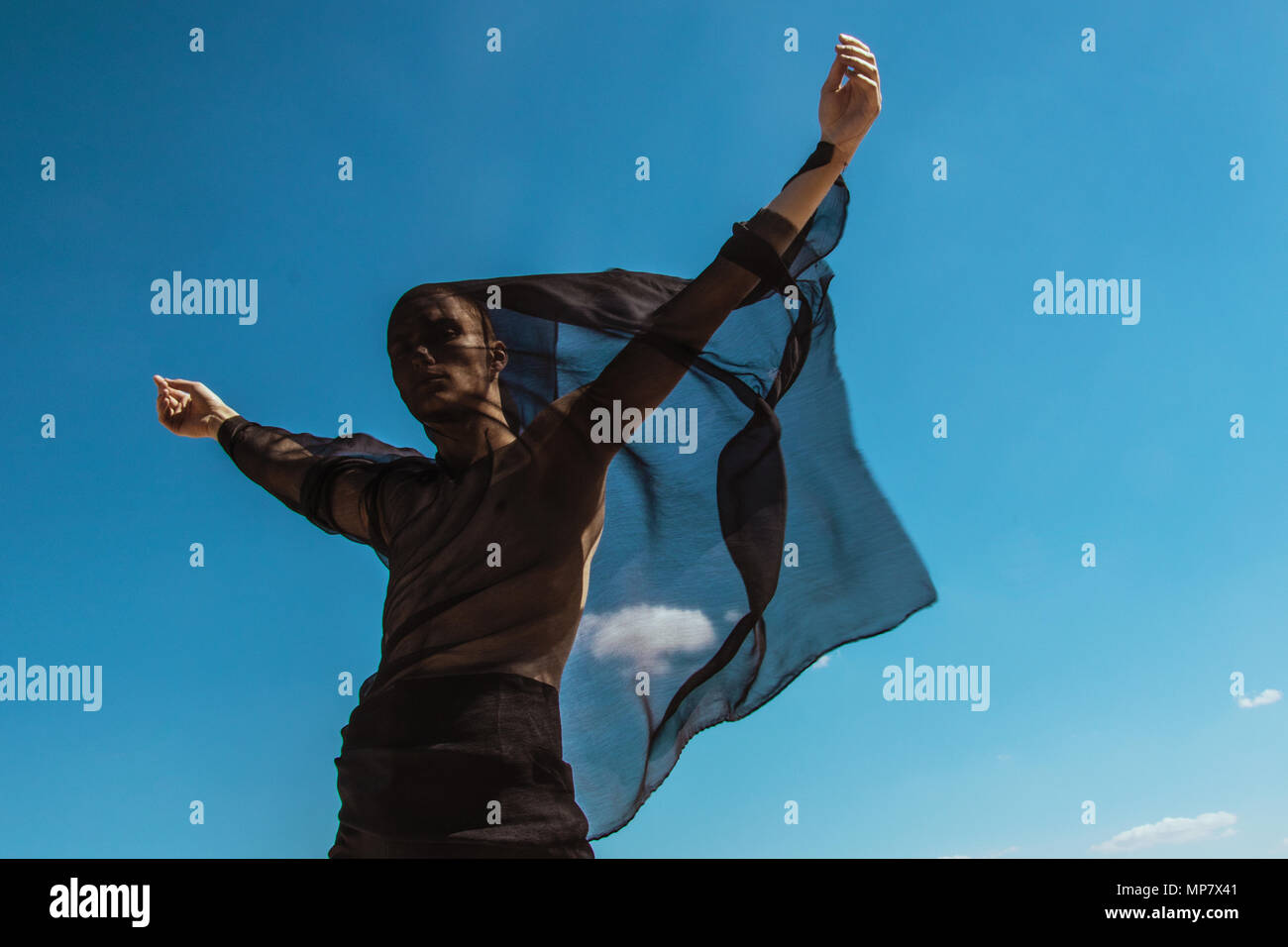 Guy with black scarf and wind on sky background in dessert Stock Photo