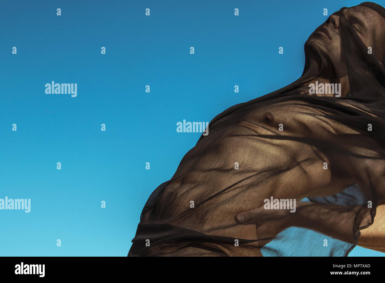 Guy with black scarf and wind on sky background in dessert Stock Photo