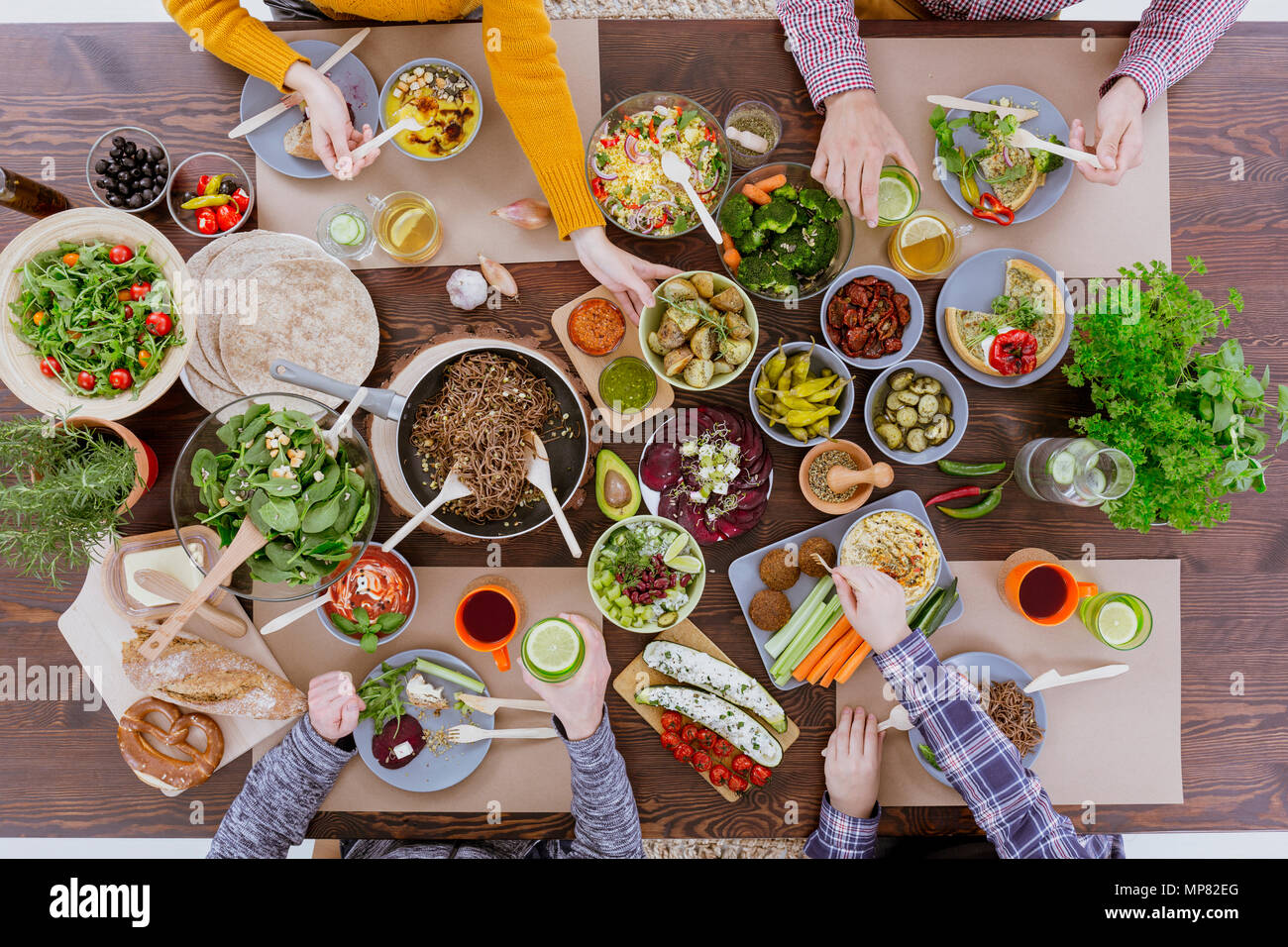 People having veg meal, sitting at wood communal table Stock Photo - Alamy