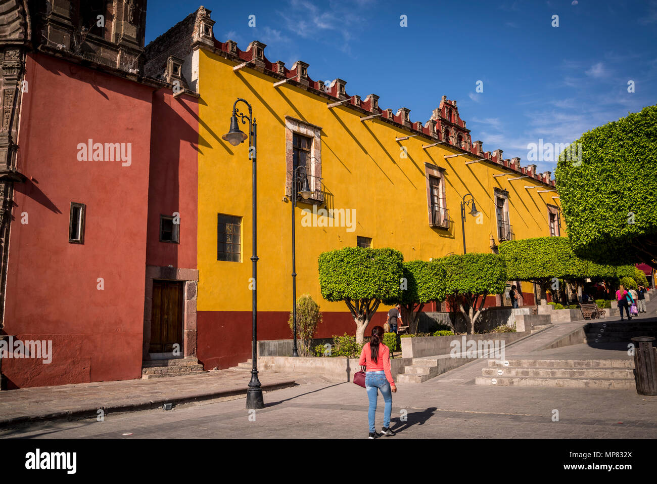 Plaza Civica with typical round shaped trees and University building, San Miguel de Allende, a colonial-era city,  Bajío region, Central Mexico Stock Photo