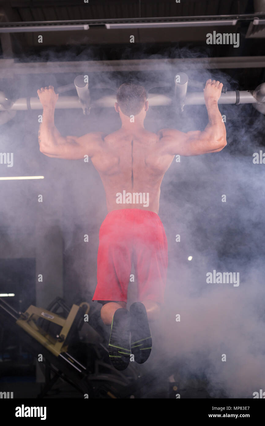 Strong young man doing pull up exercise on horizontal bar in gym Stock ...