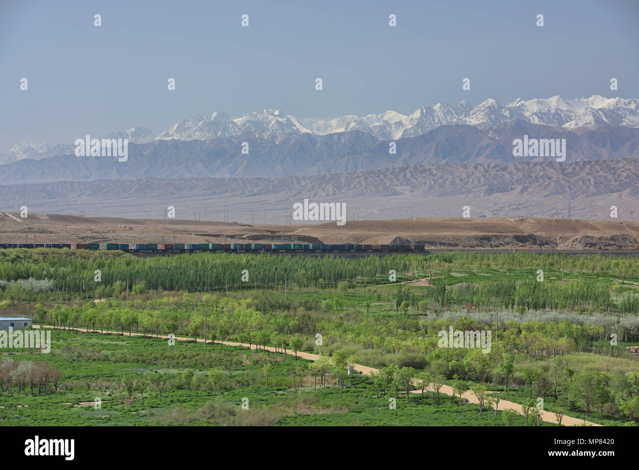 Train passing through Silk Route scenery: Qilian Mountains and desertscape, Jiayuguan, Gansu, China Stock Photo