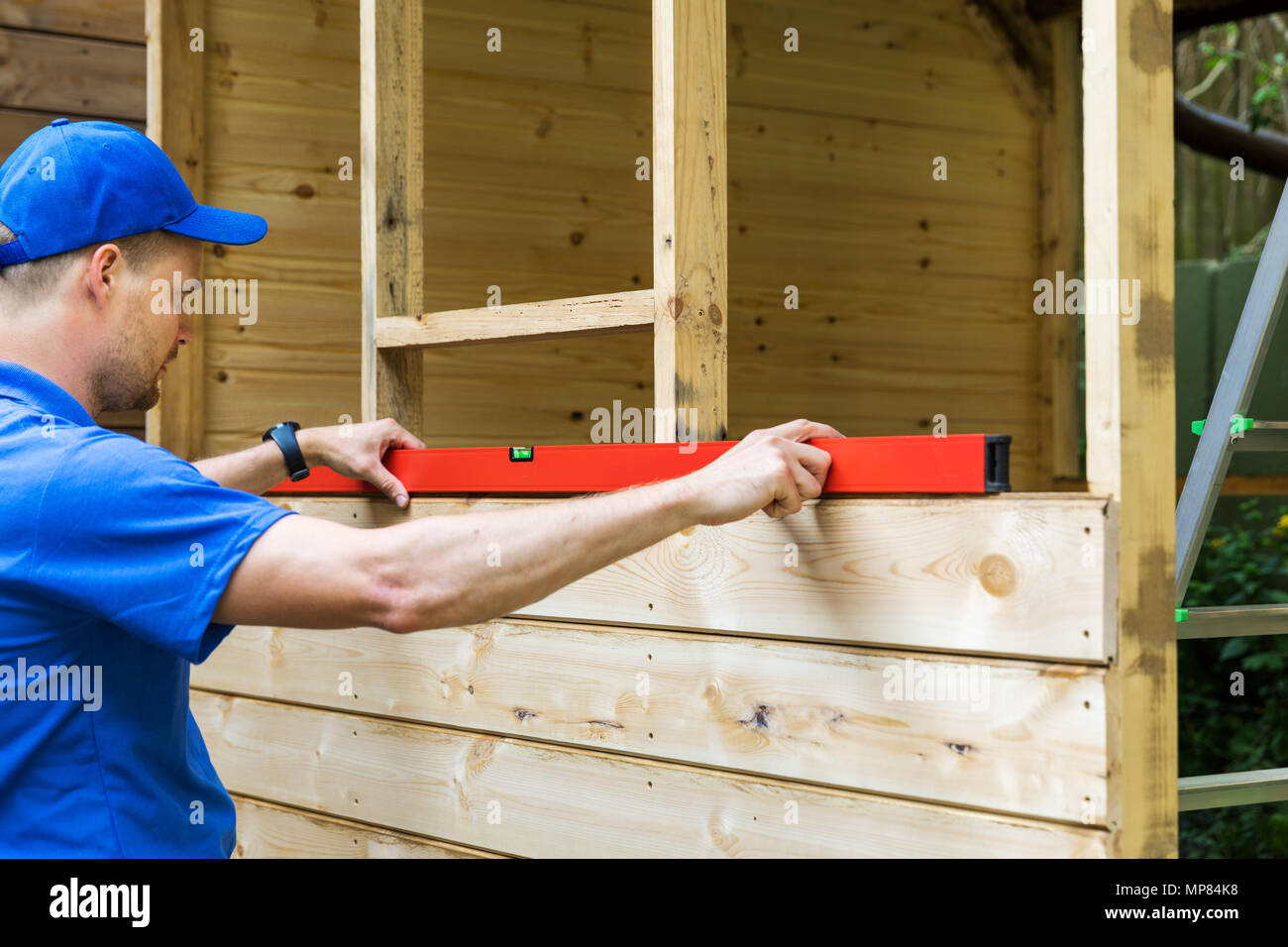 shed construction - worker check the level of wooden plank wall Stock Photo