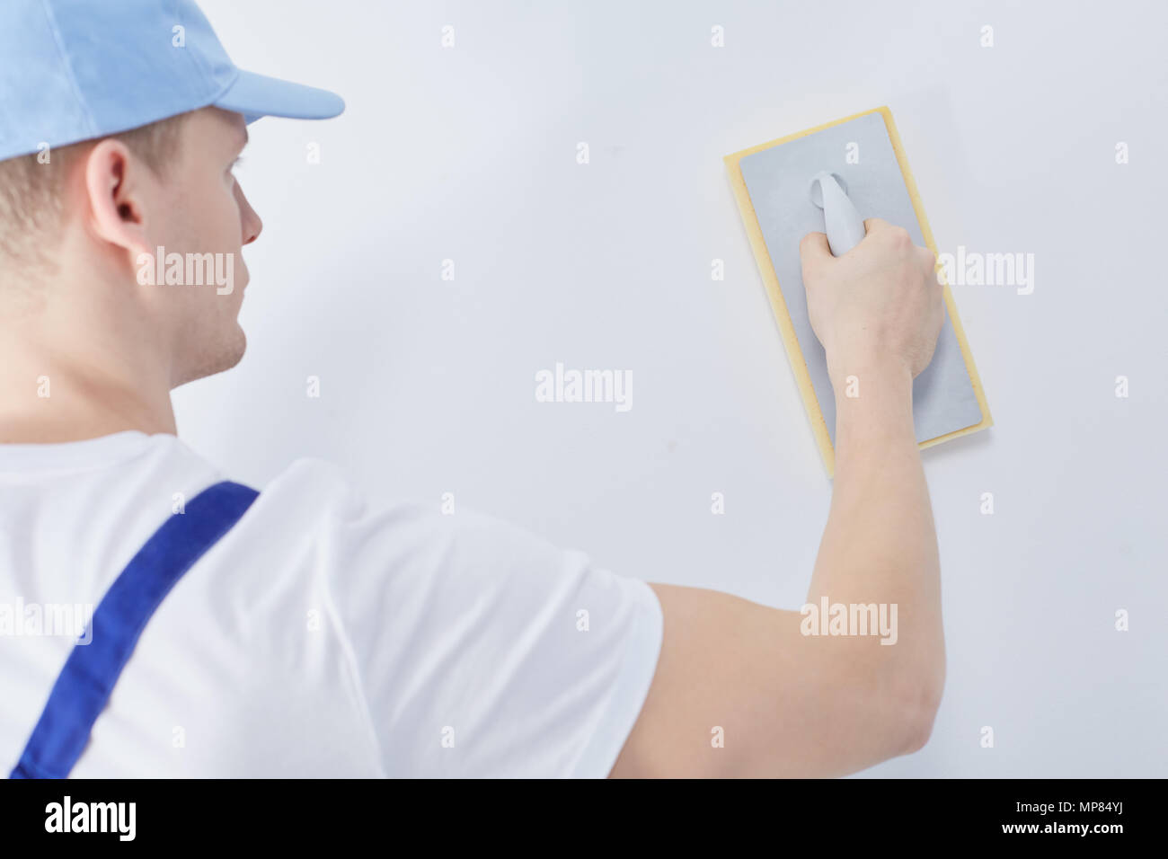 Interior construction worker with plastering trowel rubbing down the wall Stock Photo