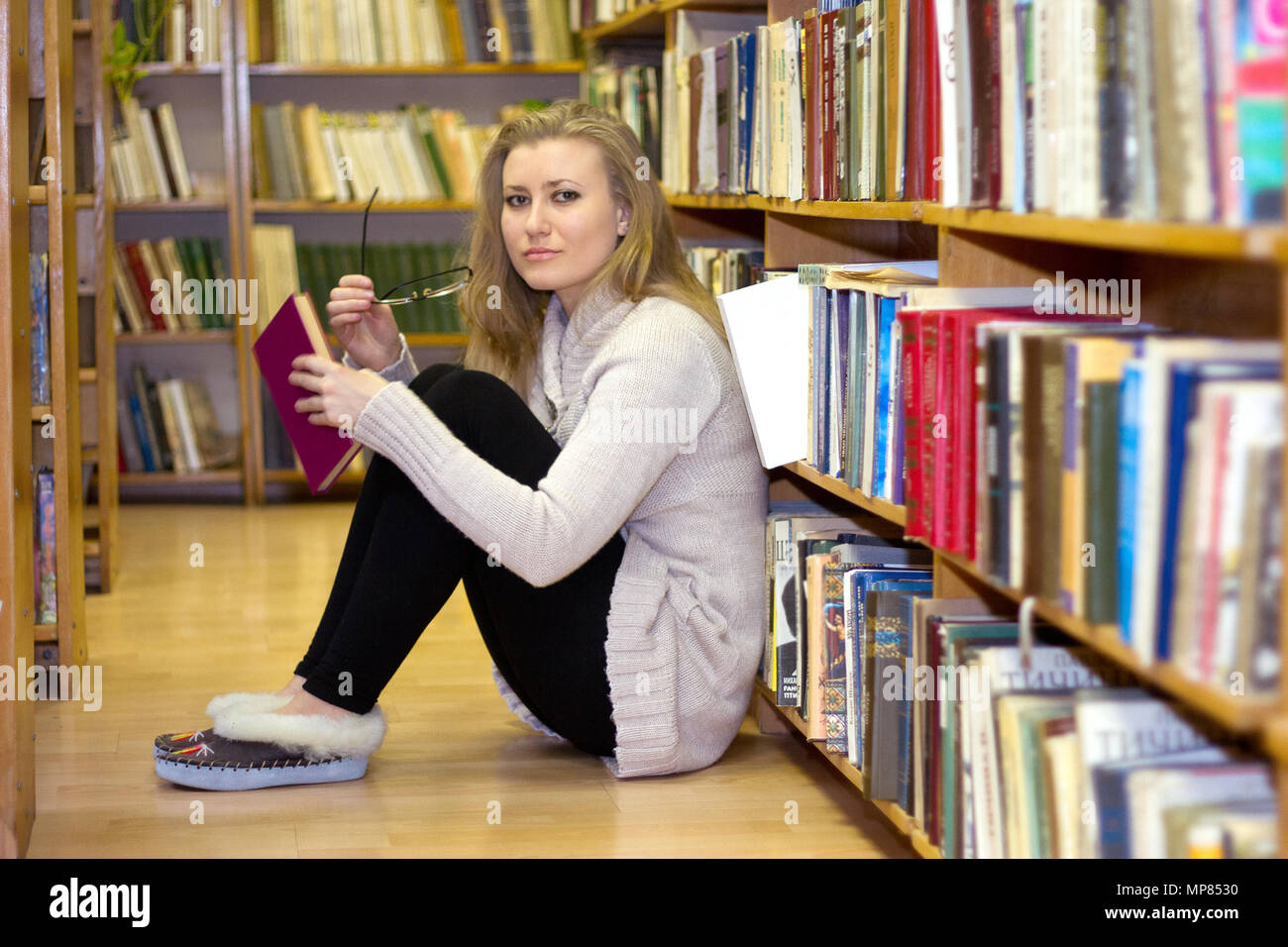Girl sitting on the floor in the old library of books Stock Photo - Alamy