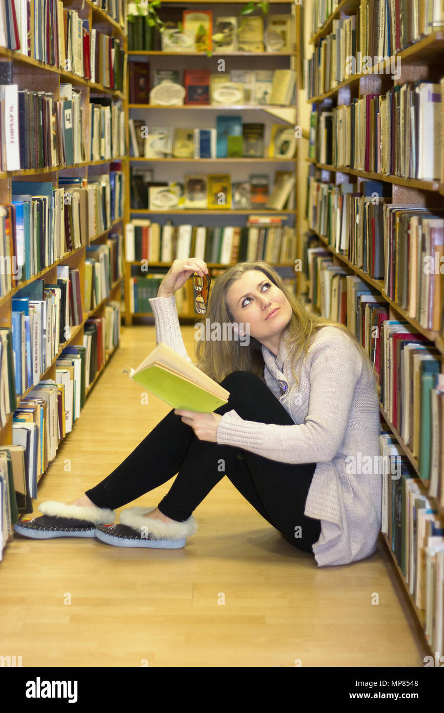 Girl sitting on the floor in the old library of books Stock Photo - Alamy