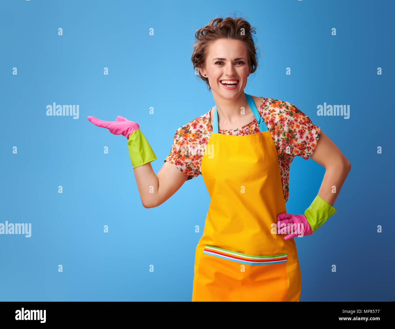 Big cleaning time. smiling young housewife in a yellow apron presenting ...