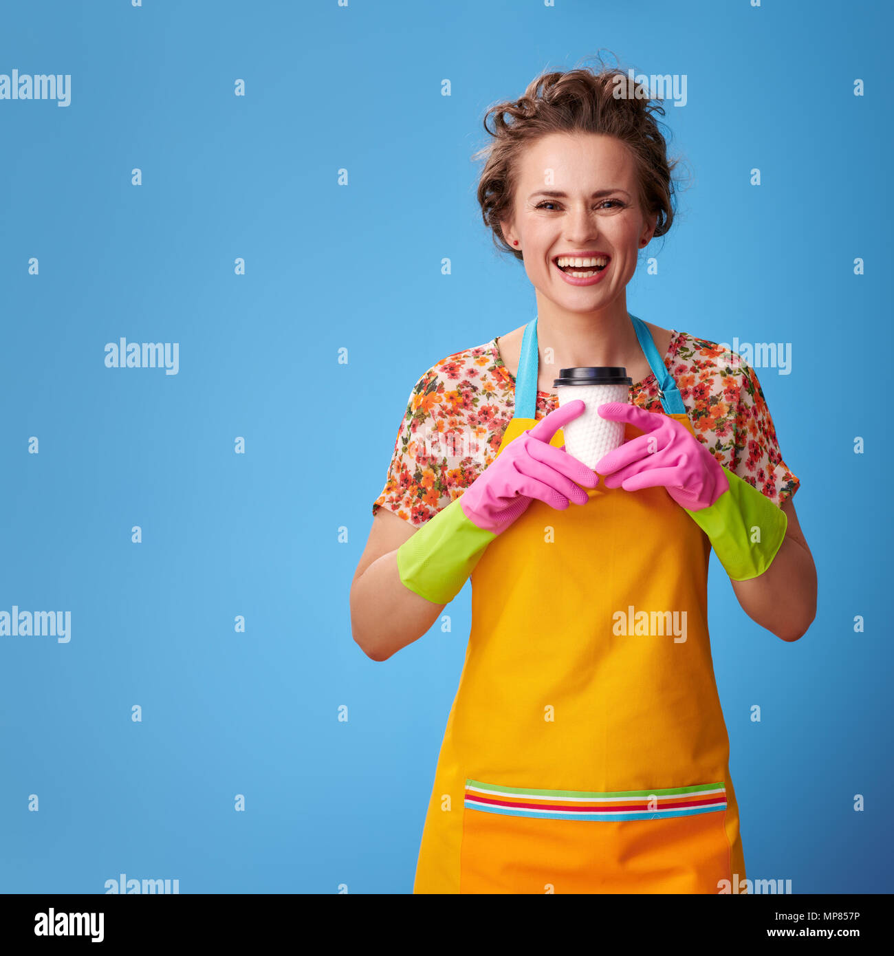 Big cleaning time. smiling modern housewife in a yellow apron holding a ...