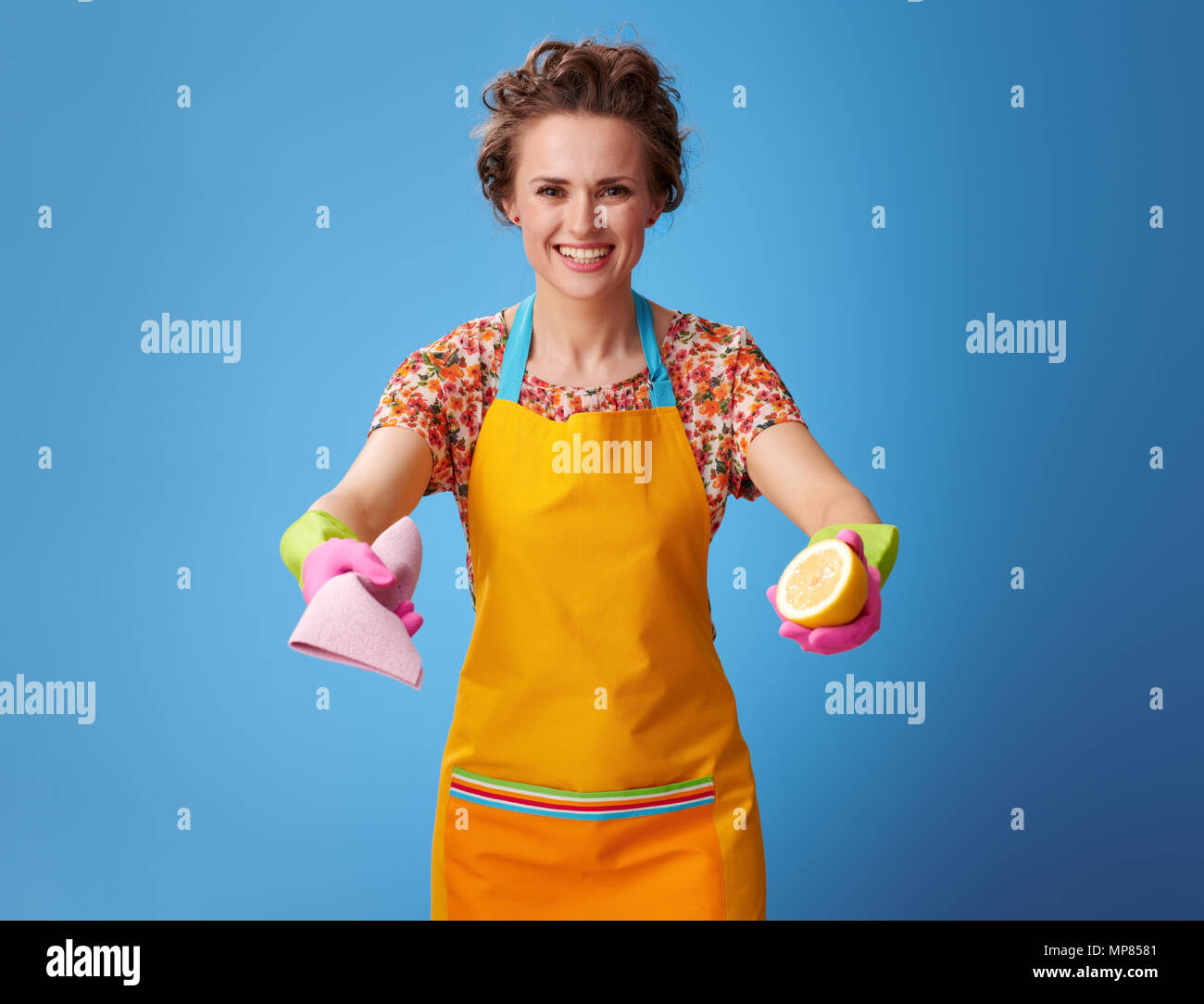 Big cleaning time. smiling modern housewife in a yellow apron giving ...
