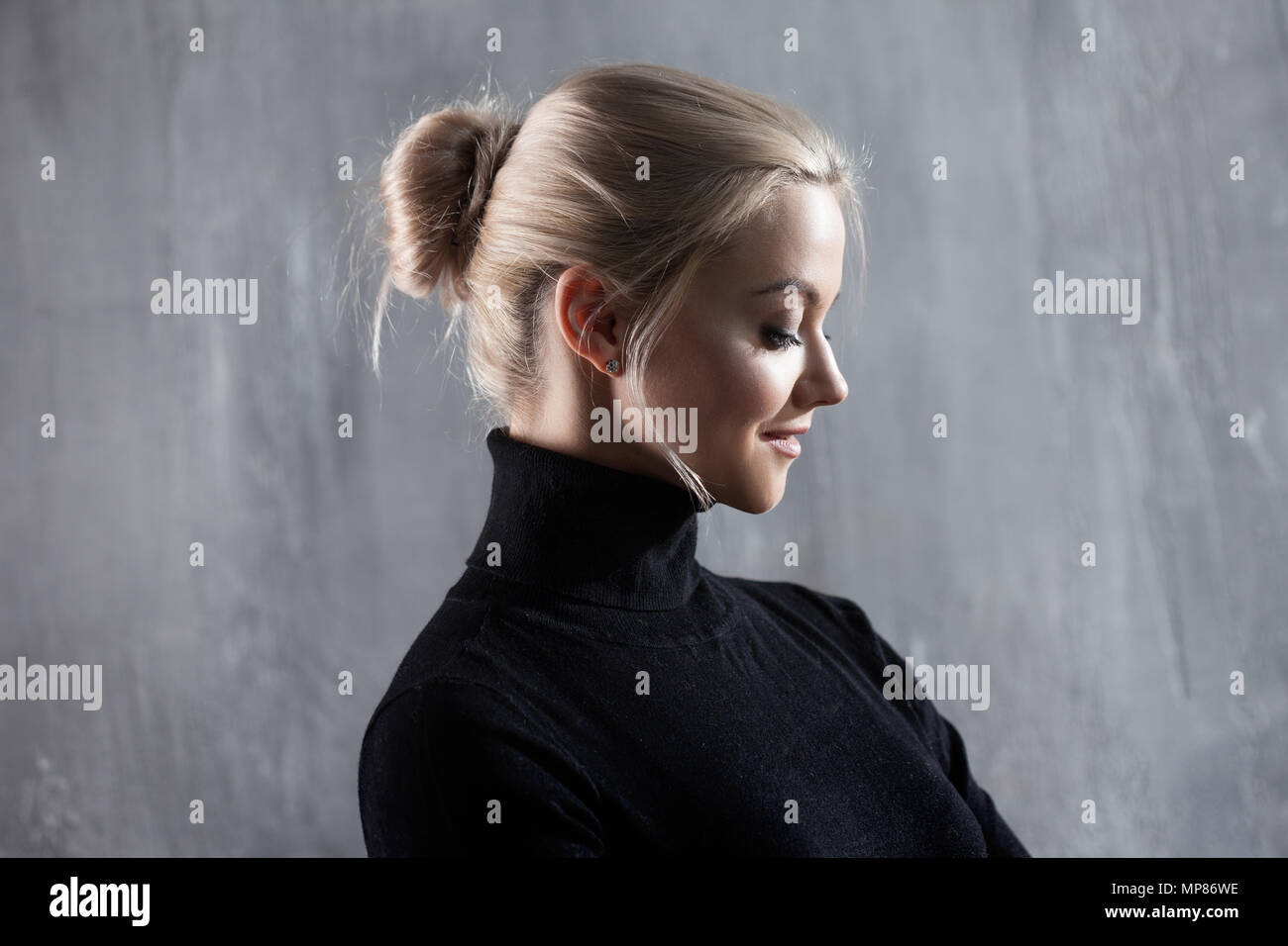 Portrait of beautiful blonde woman. Calm and self-confidence. Beautiful adult girl in black turtleneck, gray background. Stock Photo