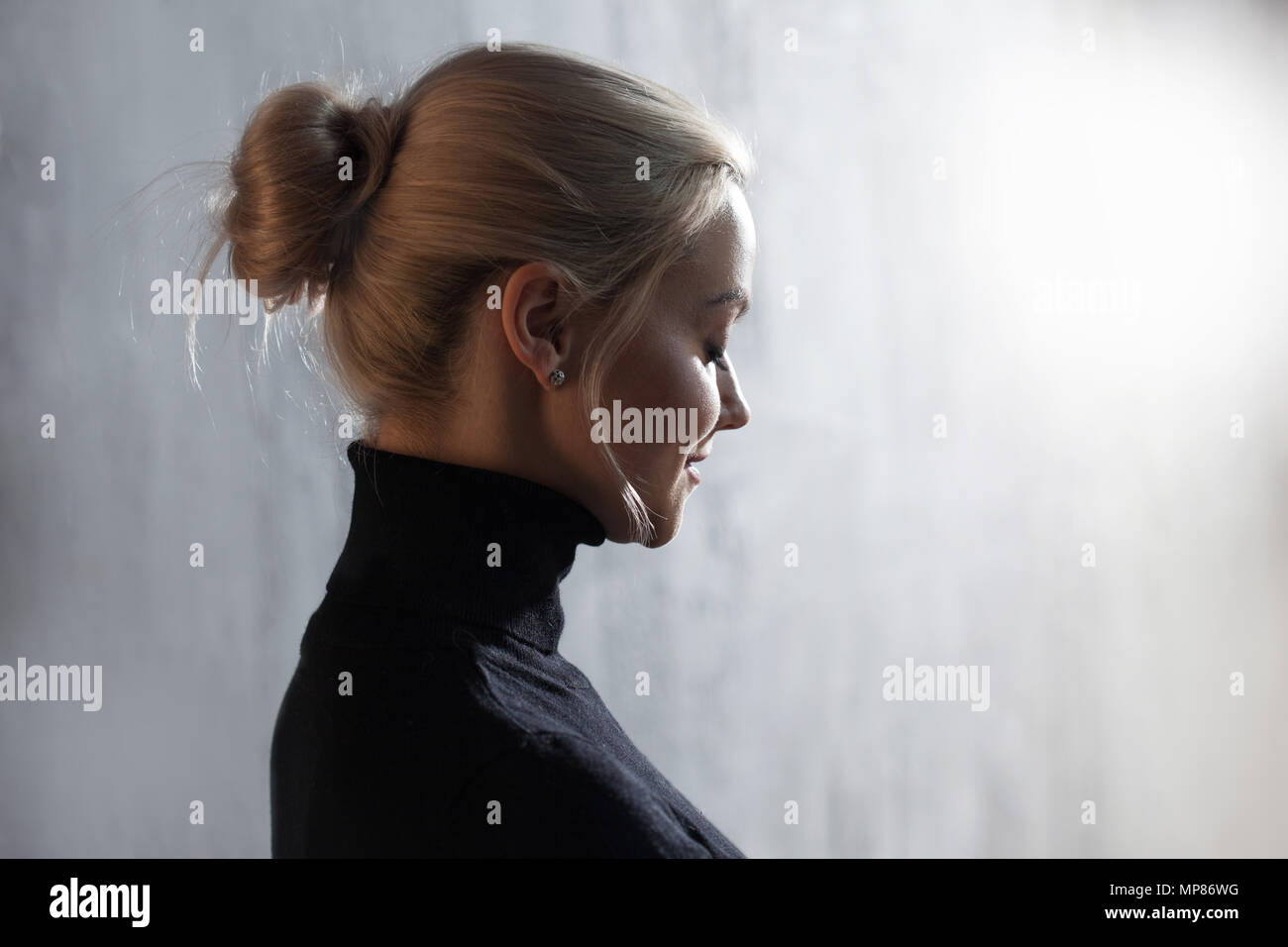 Portrait of beautiful blonde woman. Calm and self-confidence. Beautiful adult girl in black turtleneck, gray background. Stock Photo