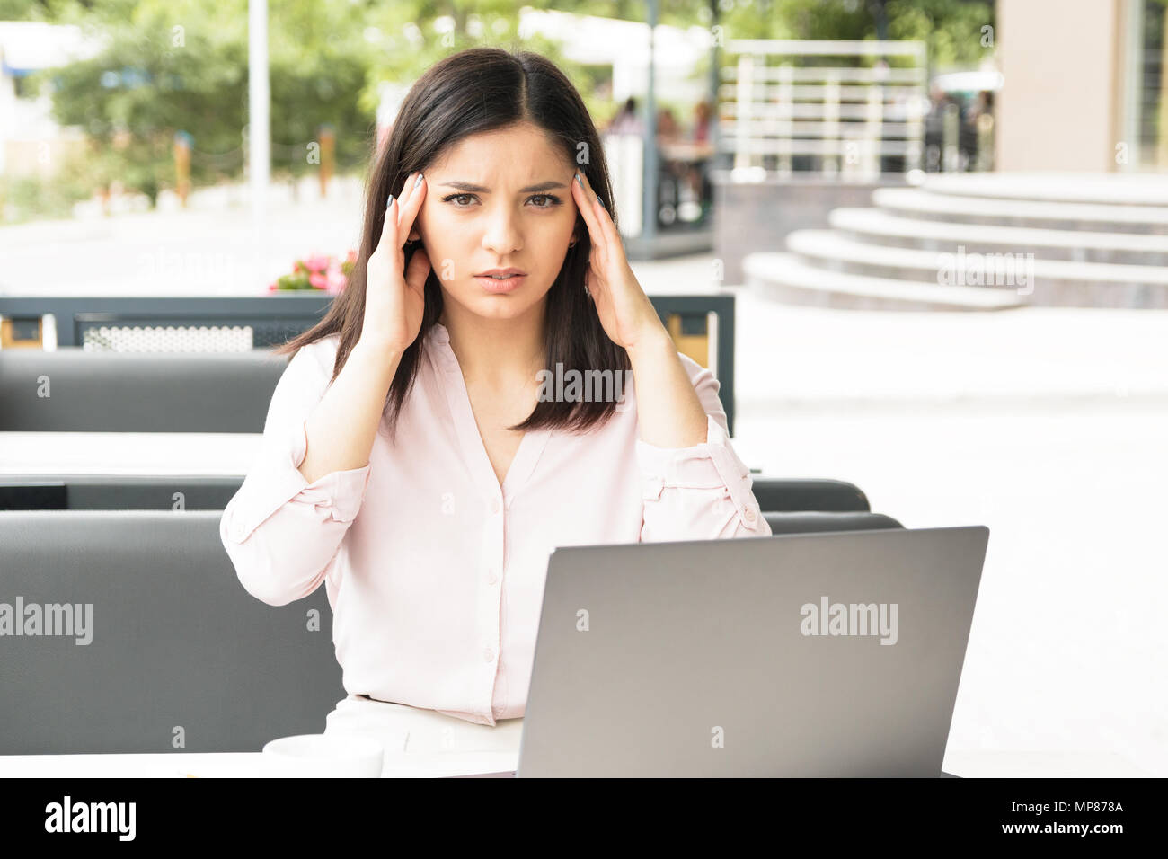 Young woman massaging her temples at work in office, too much work ...