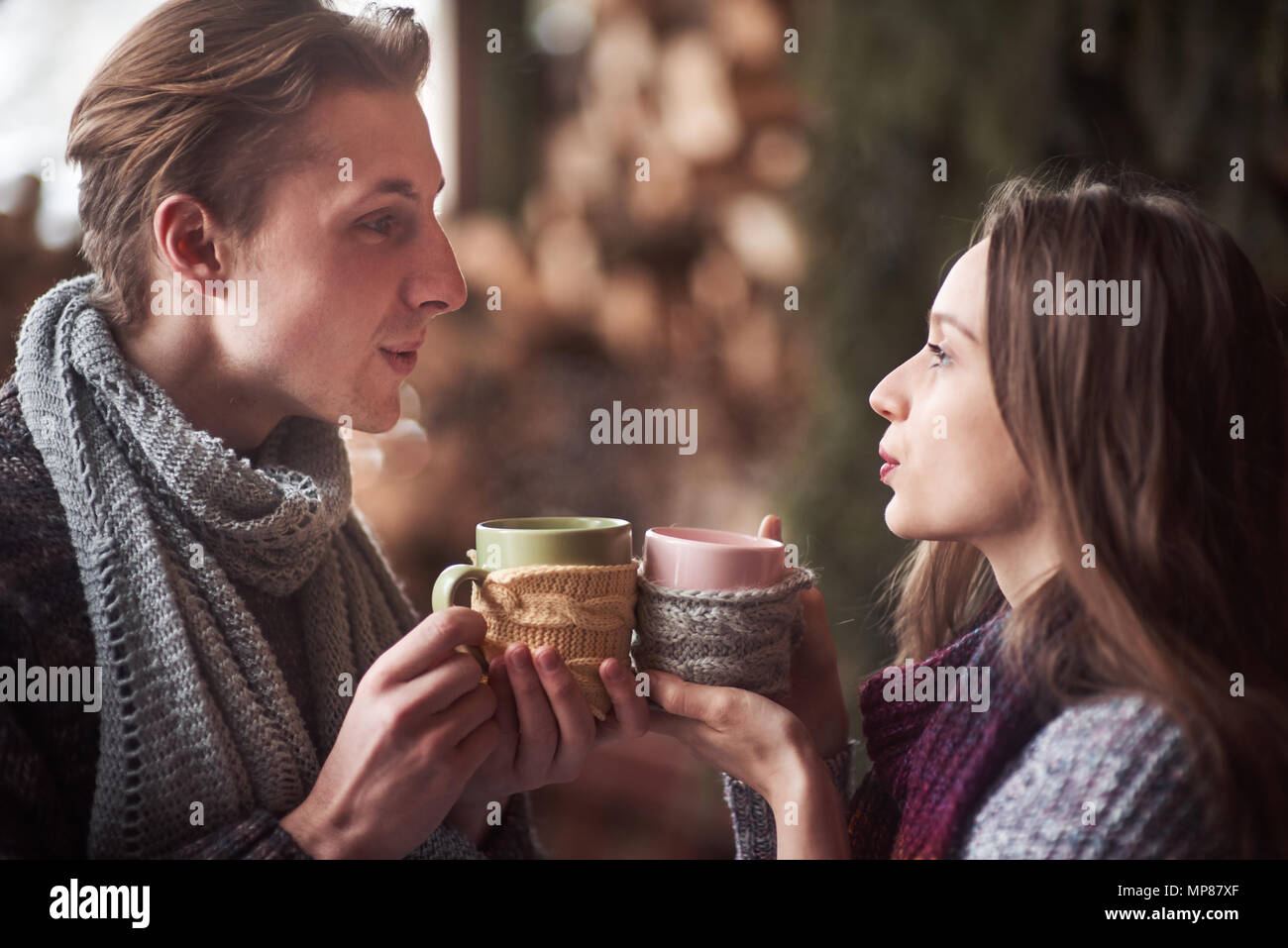 Photo of happy man and pretty woman with cups outdoor in winter. Winter holiday and vacation. Christmas couple of happy man and woman drink hot wine. Couple in love Stock Photo