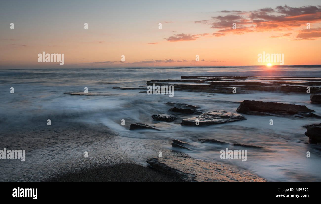 Dramatic beautiful sunset on a rocky coast at Akrotiri area in Limassol, Cyprus. Long exposure photography Stock Photo