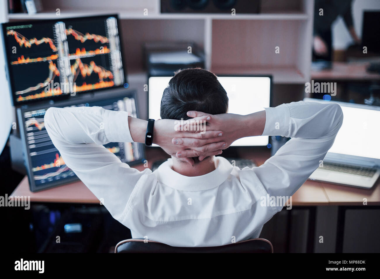 Developing new approaches. Rear view of young man in casual wear holding hand on the back of the head and working while sitting at the desk in creative office Stock Photo