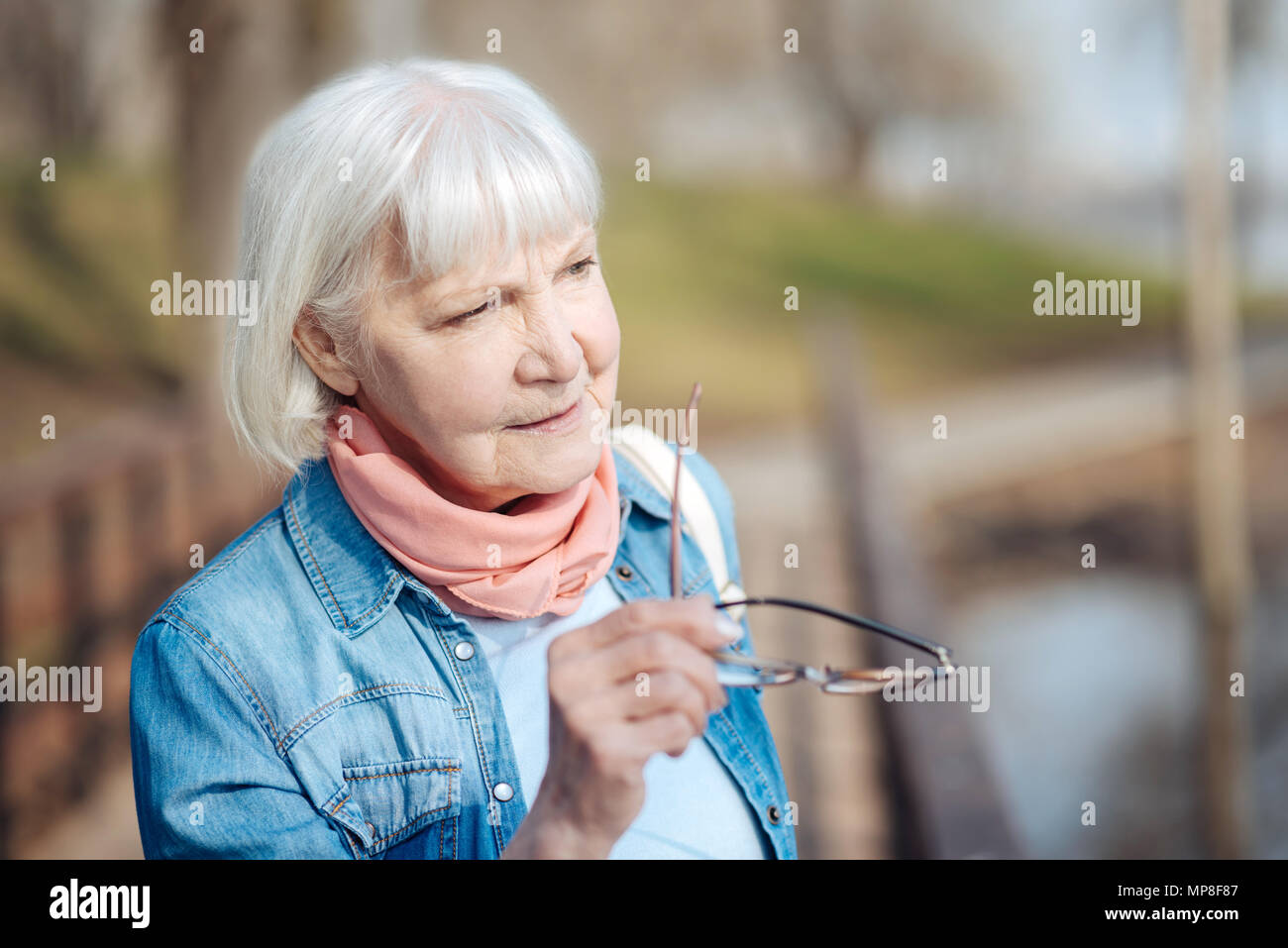 Serious old woman holding her glasses Stock Photo - Alamy