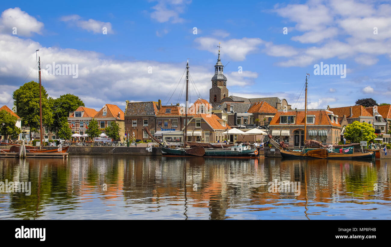 BLOKZIJL, THE NETHERLANDS - JULY 13, 2017: Harbor in the historic village of Blokzijl on sunny summer day with old flat bottom ships and monumental ho Stock Photo