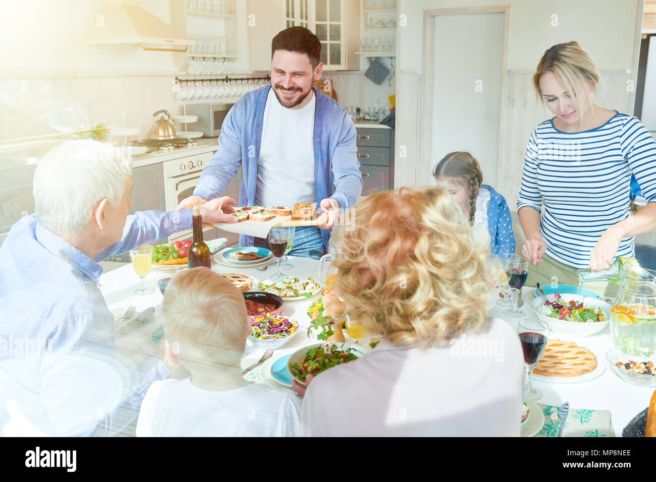 Family Enjoying Dinner in Sunlight Stock Photo - Alamy