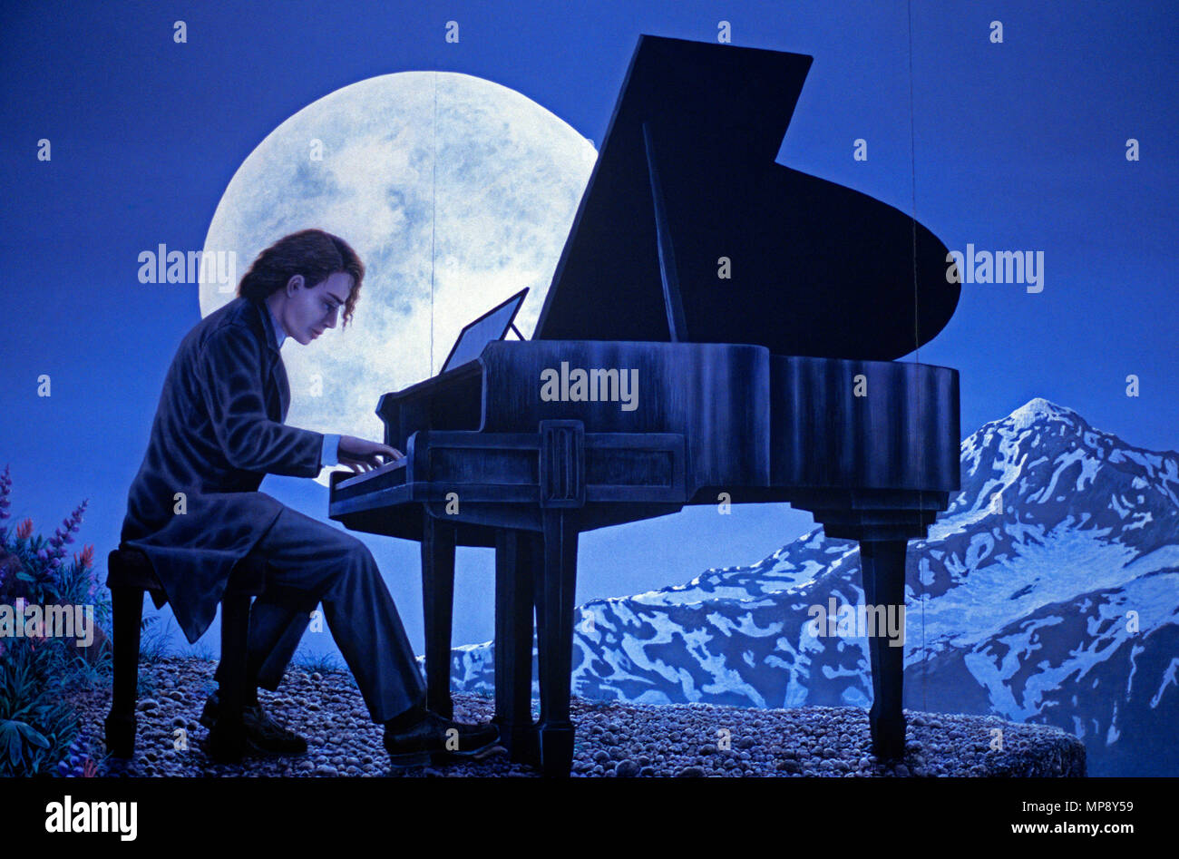 Mural depicting musician playing piano with moon rising behind him with  mountain snow Stock Photo - Alamy