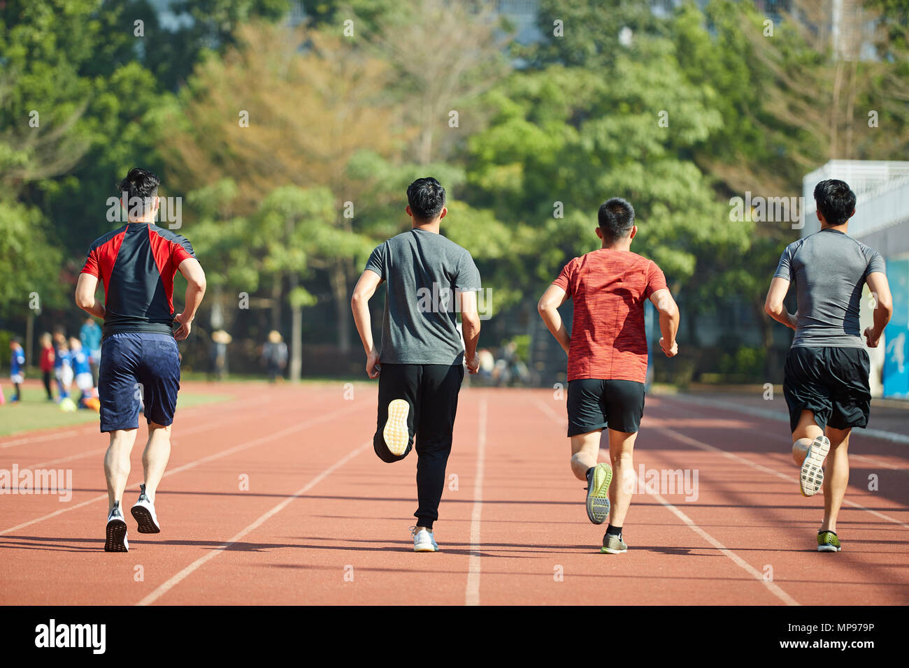 young asian adult athletes running training on track, rear view. Stock Photo