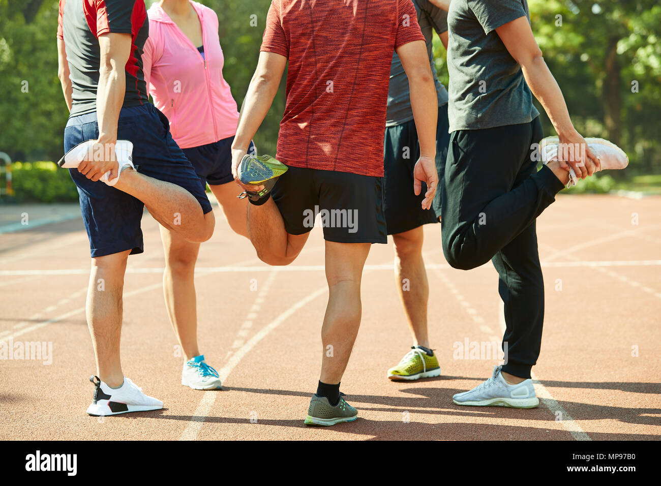 group of young asian adults warming up stretching legs on track. Stock Photo