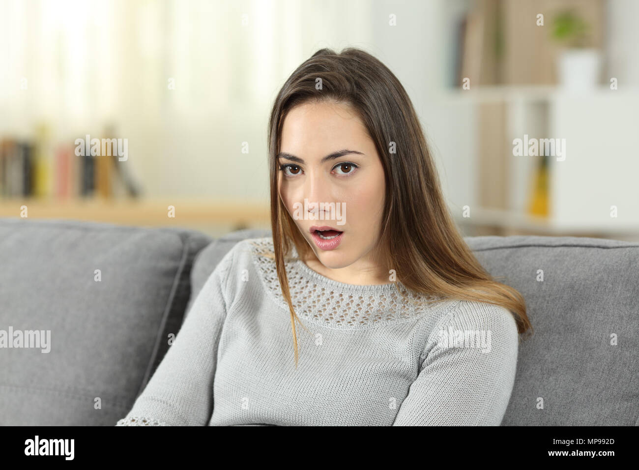 Portrait Of A Perplexed Woman Looking At Camera Sitting On A Couch In The Living Room At Home 4884