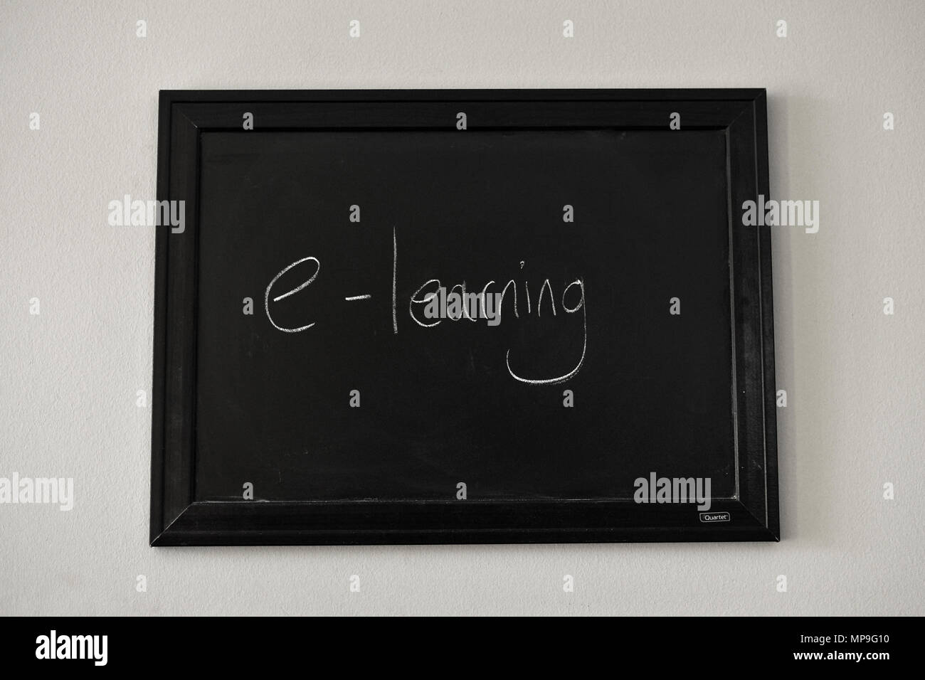 e-learning written in white chalk on a wall mounted blackboard. Stock Photo