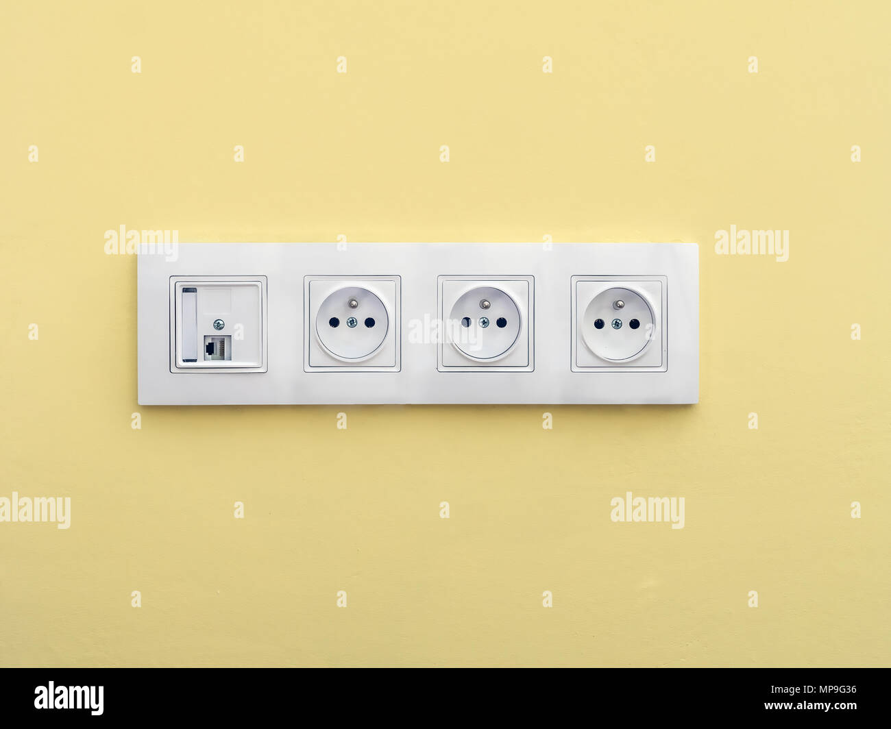 Quadruple wall socket set with internet connection mounted onto yellow wall Stock Photo