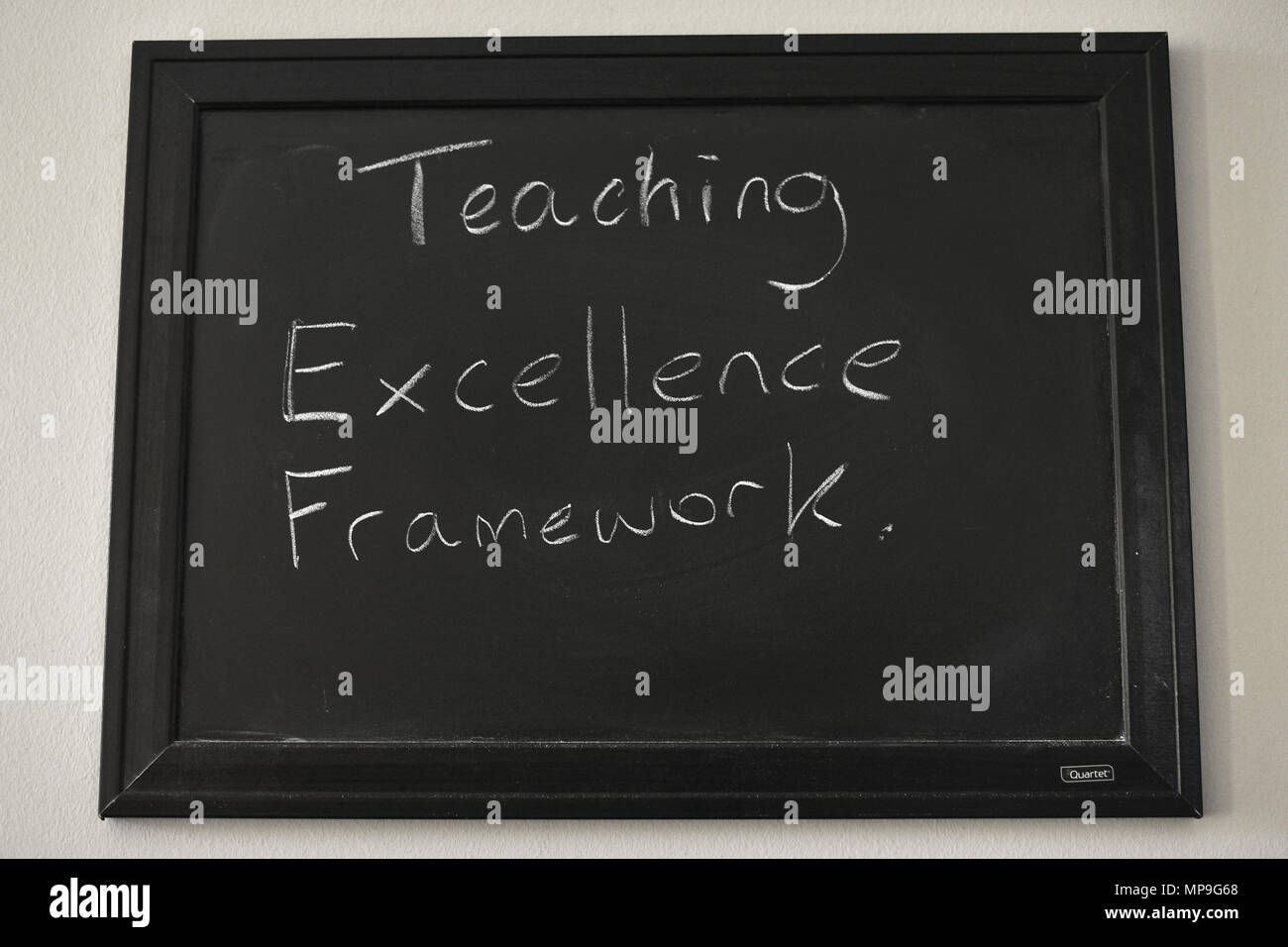 Teaching Excellence Framework written in white chalk on a wall mounted blackboard. Stock Photo