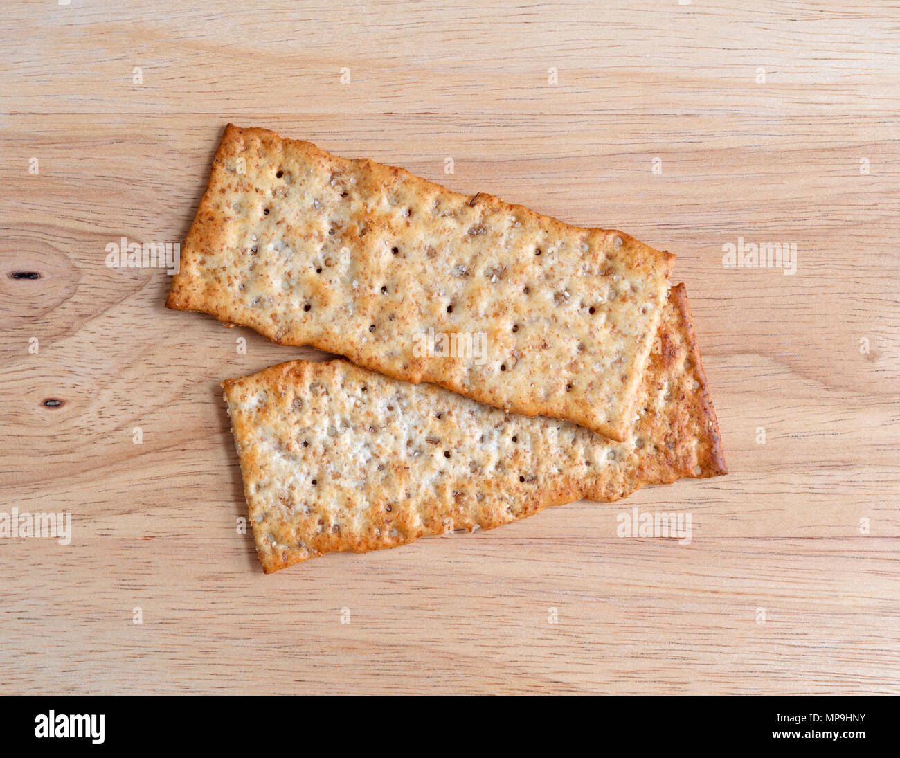 Top view of two multigrain flatbread crackers on a wood cutting board
