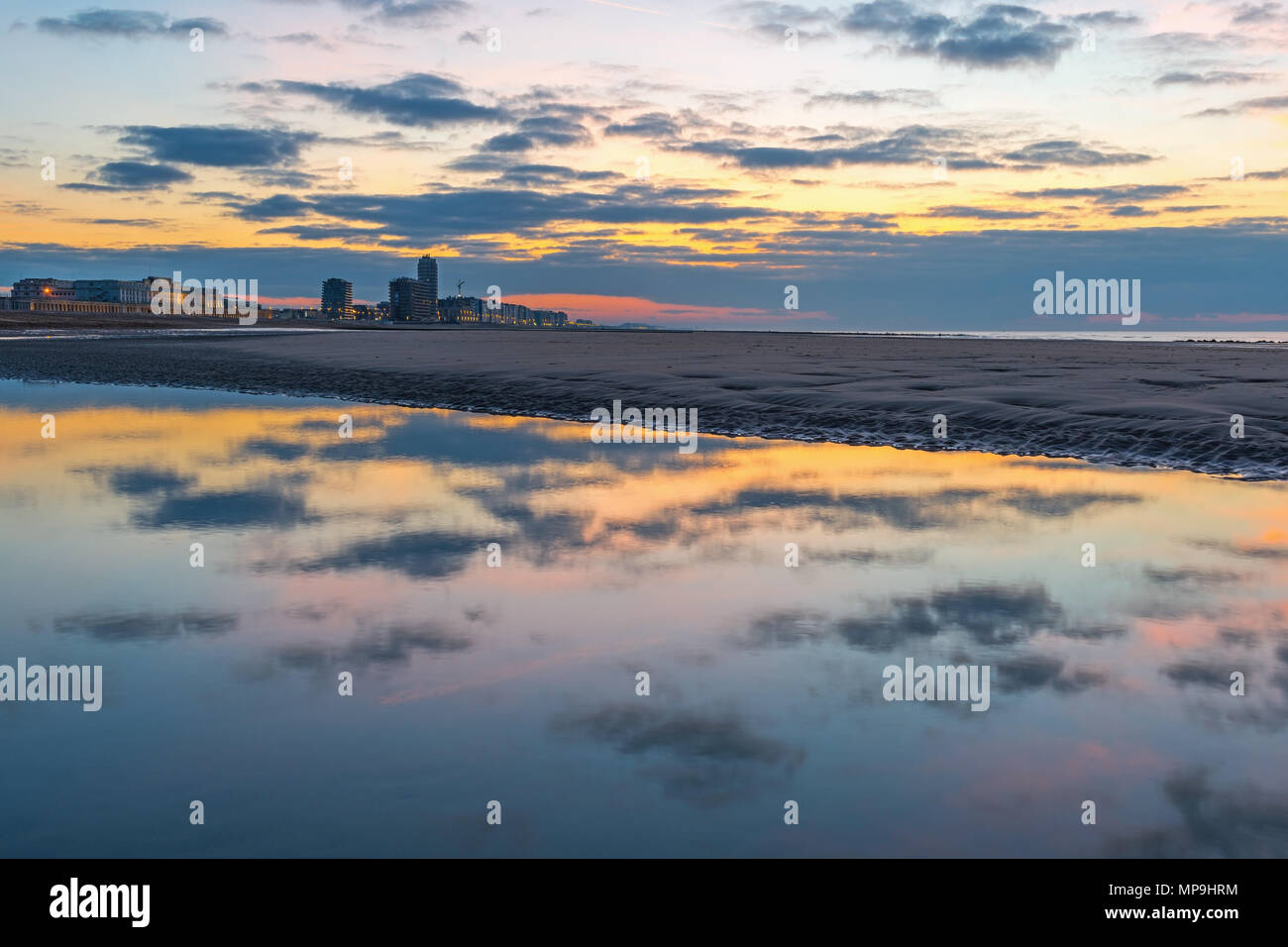 The cityscape of Ostend city and its beach reflecting in the North Sea at sunset in summer, West Flanders, Belgium. Stock Photo