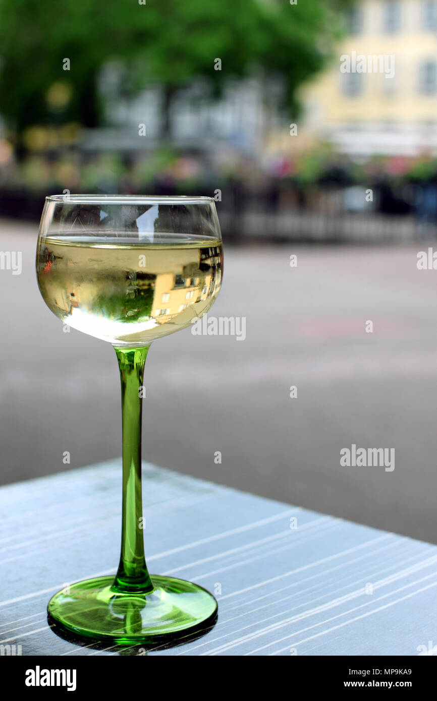 Glass of white wine on the table. Blurred background. Vertical side view image with space for text. Stock Photo