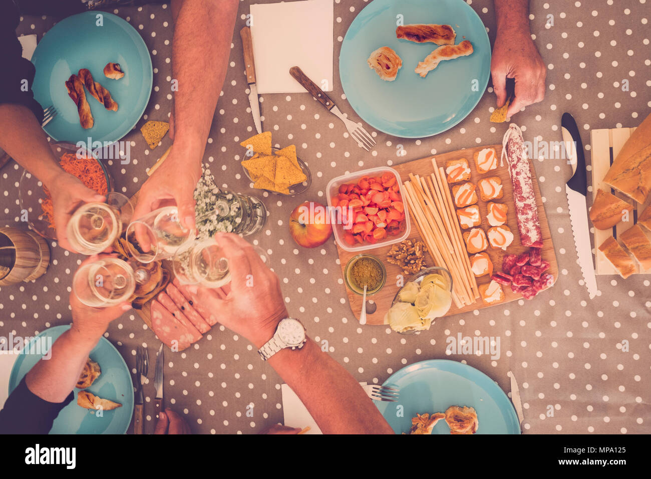 alternative point of view of people having lungh or dinner at home. aged seniors two couple on the table drinking wine and eating food. colors and dot Stock Photo