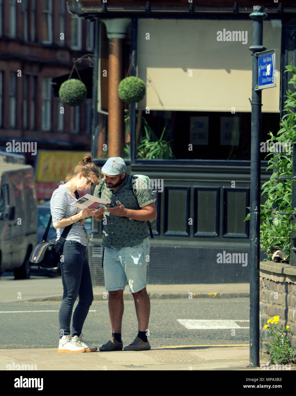 tourist couple man and a woman consult  a map on street corner Stock Photo